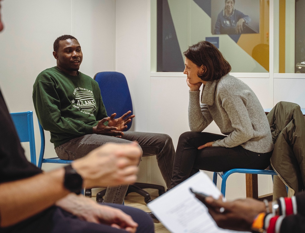 Un échange entre un candidat et une coach, entourés d’autres participants